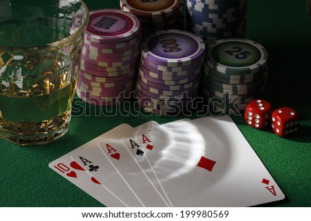 Poker/Four cards, glass of whiskey and chips,dices on poker table