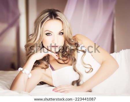 Portrait of young beautiful blonde in stylish underwear sitting in her white vintage bedroom. Healthy skin and natural make-up. Vogue style. Indoor shot