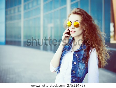 Technology internet and happy people concept - beautiful successful  woman in sunglasses talking on cellphone while walking outdoor. City business   woman working. Urban style.