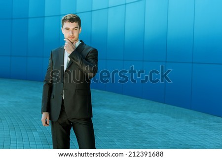 Handsome men in full suit. Full length of confident young businessmen standing over blue wall