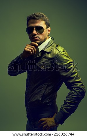 Fashion portrait of young handsome man model in trendy glasses, leather jacket and jeans. Close up. Copy space