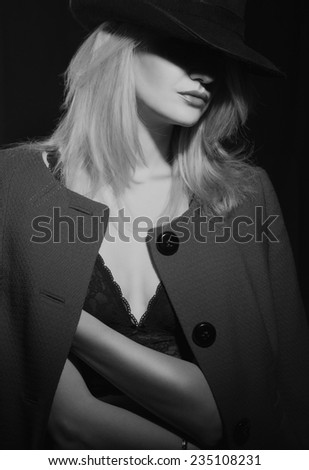 Mysterious fashion portrait of blond woman with red lips in black hat and trendy jacket. Lady in red.
