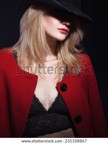 Mysterious fashion portrait of blond woman with red lips in black hat and trendy jacket. Lady in red.
