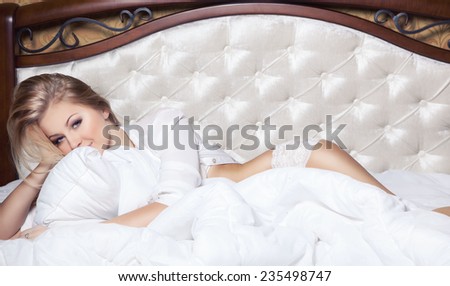 Glamour blond sexy girl in white underwere over comfortable blanket and pillow in luxury bad.