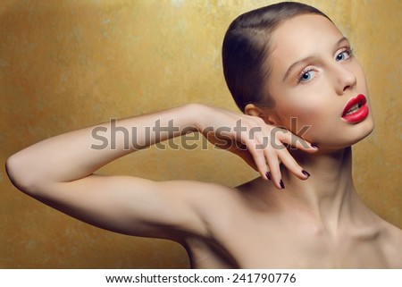Close up fashion portrait of young beautiful woman with clean fresh skin, perfect make up and nails over golden background.