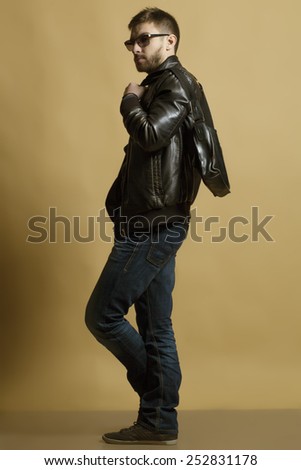 Fashion portrait of handsome young man in trendy casual jacket,  jeans with bag.
