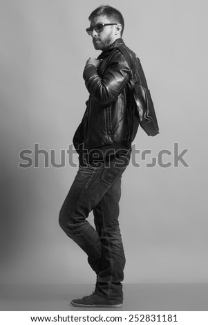Monochrome Fashion portrait of handsome young man in trendy casual jacket,  jeans with bag.