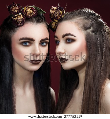 Two beautiful women with art wide eyebrows and brown lipstick and roses in hairs. Gothic make up.