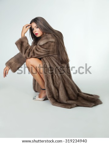 Luxury beautiful woman in fur mink coat with vest looking at camera over white background.