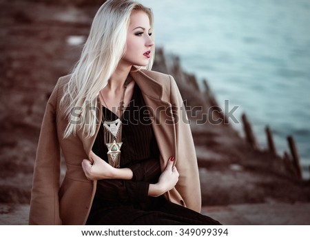 High fashion photo of elegant woman in black long dress, coat and stylish necklace in boho style.