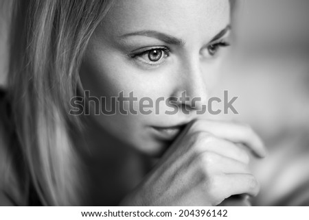 Black and white emotive portrait of young beautiful woman with long blonde hair. Close up