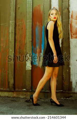 Hipster style. Fashion portrait of beautiful blond-haired girl in trendy black crop top and skirt posing over rusty metal background. Perfect skin and make-up. Outdoor shot
