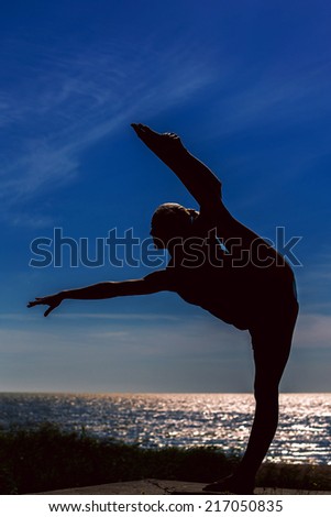 Girl dances on the beach at sunset. Natural light and darkness. Artistic colors added.