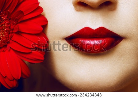 Close-up shot of sexy woman lips with red lipstick and beautiful red flower