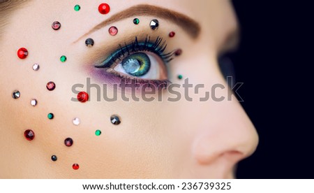 Arty make-up on woman eye with diamonds around. Perfect skin. Close up. Retro style. Studio shot