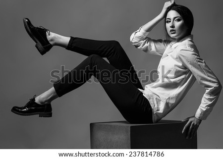 Female beauty concept. Portrait of fashionable young girl in classic clothes posing over gray background. Perfect hair & skin. Vogue style. Studio shot