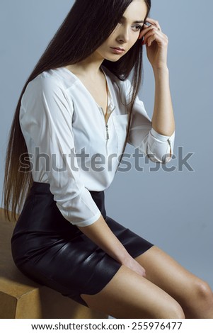Female beauty concept. Portrait of fashionable young girl in classic clothes posing over grey background. Perfect hair & skin. Vogue style. Studio shot