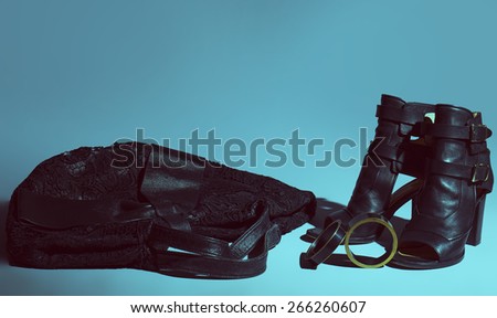 fashion concept of woman style. Trendy leather women\'s shoes with black bag and  bracelet over  blue background. Close up. Studio shot. Stylish and arty casual shoes.