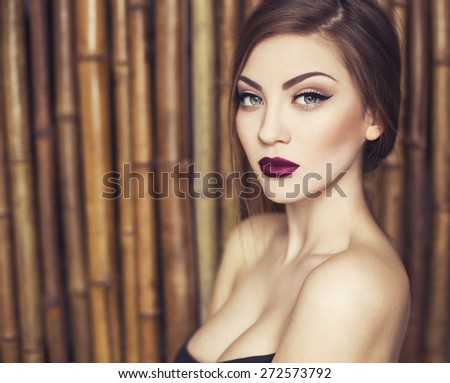 Sexy Beauty Girl with purple-red Lips. Provocative Make up. Luxury Woman with Green Eyes. Fashion Brunette Portrait on a bamboo (natural) background. Gorgeous Woman Face. Long Hair