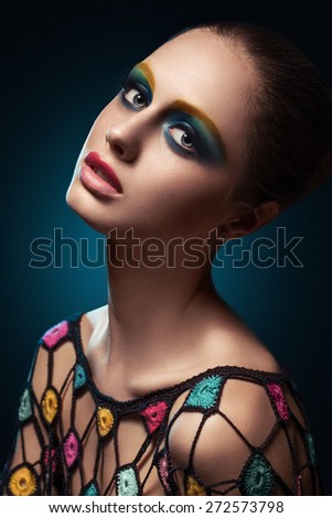 Close-up of beautiful female face with colorful make-up.Beauty. Fresh glowing skin. Accessory.Flower.Blue.Art.Theater.Face art.Bright.Closeup.Portrait.Look Fashion make-up. Fantastic Modern production
