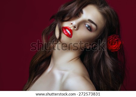 Beautiful Sexy fashion Woman with rose in her hair.  Makeup with Red Lips, long perfect hair and Red rose. Beauty italian Girl. Passion. Close up. Copy space