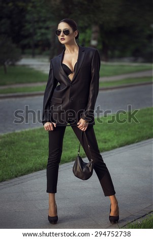 Female beauty concept. Portrait of fashionable young girl in classic clothes (suit) and sunglasses posing on the street. Perfect hair & skin.  outdoor shot