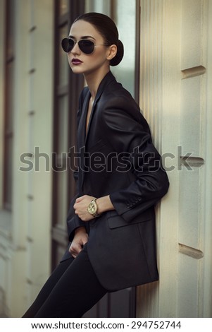 Female beauty concept. Portrait of fashionable young girl in classic clothes (suit) and sunglasses posing on the street. Perfect hair & skin.  outdoor shot