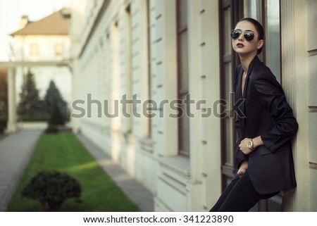 Female beauty concept. Portrait of fashionable young girl in classic clothes (suit) and sunglasses posing on the street. Perfect hair & skin. Vogue style. outdoor shot