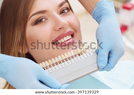 Beautiful european woman smile with healthy teeth whitening. Dental care concept. Set of implants with various shades of tone