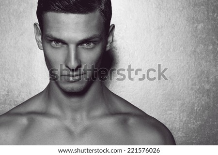 Male beauty concept. Portrait of fashionable and undressed young man with stylish haircut posing over gray background. Perfect hair & skin. Tough guy. Vogue style. Close up. Studio shot