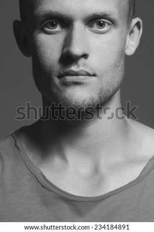 Black and white male beauty concept. Portrait of young handsome man with pensive and intense look posing over grey background. Close up. Studio shot
