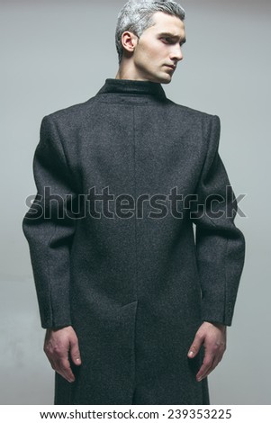 Snow Adonis fashion beauty concept. Emotive portrait of young man with stylish snow-white haircut posing over grey background. Perfect hair & skin. Vogue avant garde style. Studio shot
