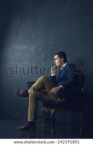 English gentleman beauty concept. Portrait of young and handsome man in blue jacket, Scottish bow-tie and white shirt posing over blue background. Close up. Studio shot