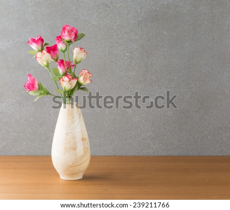 plastic rose in vase on wood table