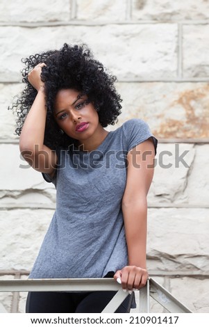 Beautiful model with afro leaning against fire escape