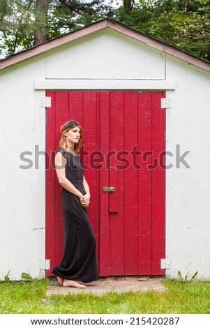 Fashionable woman wearing headpiece in front of red door