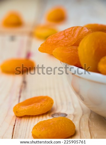 dried apricots in a bowl over wooden background, selective focus
