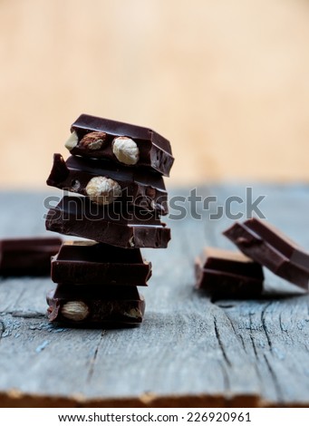 Stack of chocolate pieces on wooden background, selective focus
