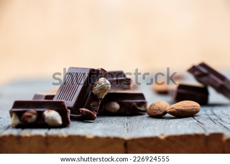Chocolate with nuts lying on wood board, selective focus