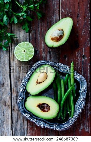 Top view of green halved avocados and beans  on rustic wooden background - healthy food, diet or cooking concept.