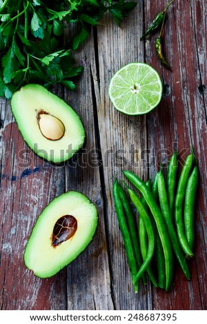 Halved avocados and green beans  on rustic wooden background - healthy food, diet or cooking concept. Top view.