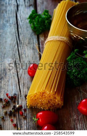 Spaghetti and tomatoes with herbs over rustic and vintage wooden background. Selective focus.