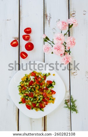 Fresh salad with vegetables on white wooden background. Healthy food, diet or cooking concept. Top view.
