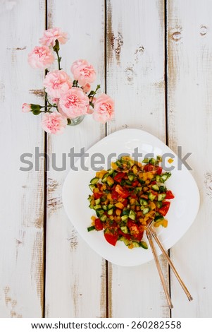 Top view of salad with vegetables on white wooden background. Healthy food, diet or cooking concept.