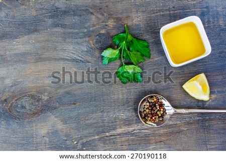 Food background with olive oil, spices, lemon and parsley on old wooden table, top view. Copy space.