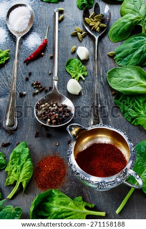 Herbs and spices in vintage metal cup and spoons over old wooden table - cooking, healthy eating.