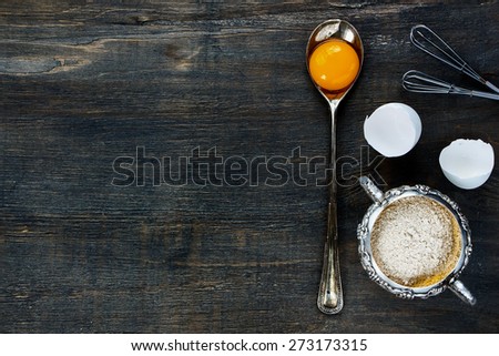 Food background with copy space - egg yolk in vintage spoon and flour in vintage cup on wooden texture. Top view.