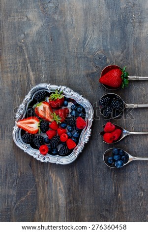 Top view of berries mixed on vintage metal plate over dark wooden background. Agriculture, Gardening, Harvest Concept.