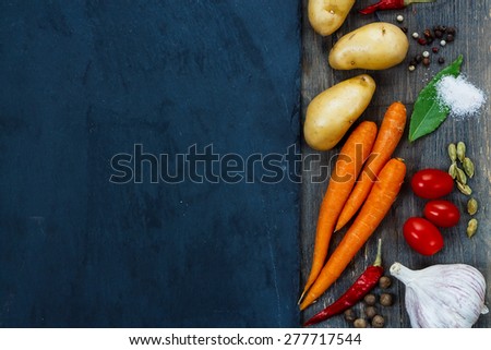 Top view of Healthy eating background with fresh organic vegetables, spices and herbs over slate. Healthy food from garden.
