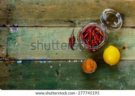 Red Hot Chili Peppers in glass jar over rustic wooden board - cooking or spicy food concept. Background with space for text.